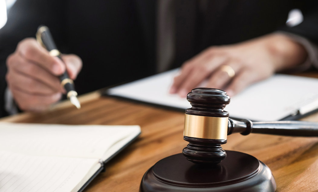 Judge signing paperwork beside a gavel