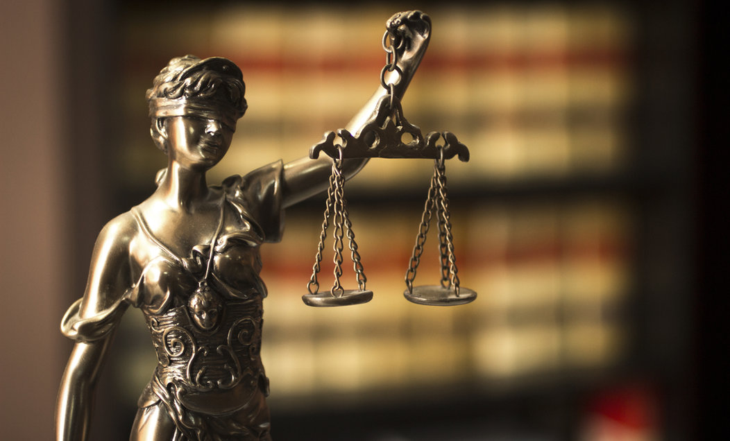 Statue of the scales of justice in front of law books