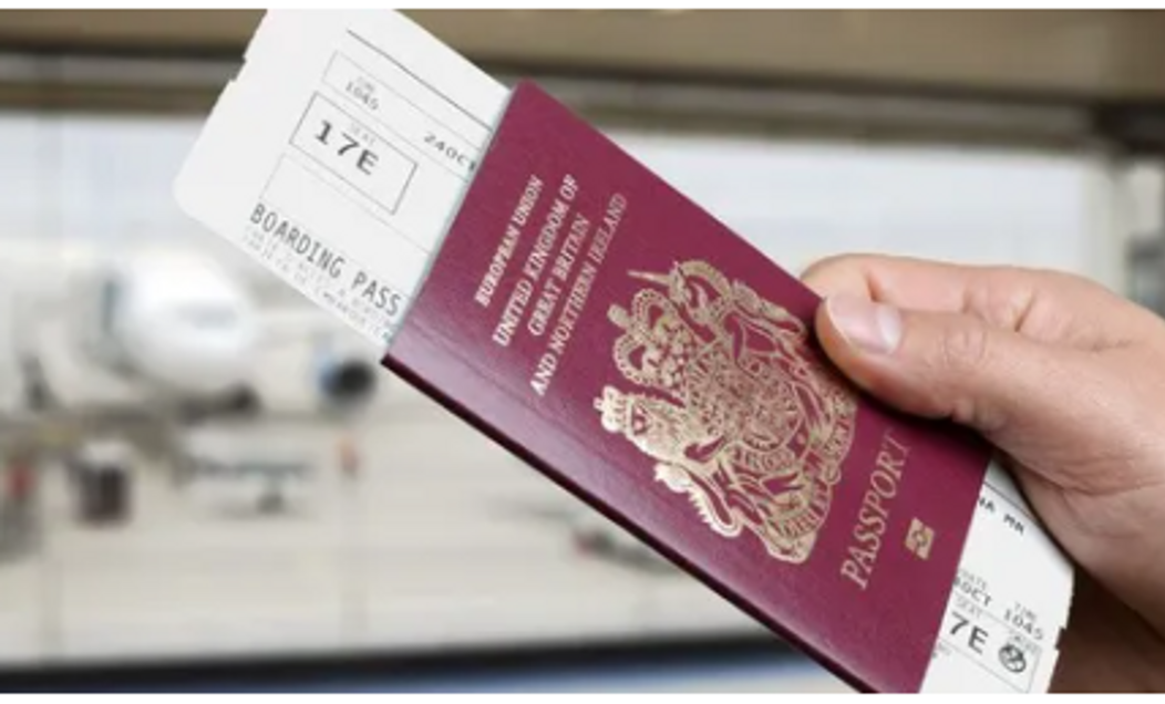 Hand holding a British passport and boarding pass at the airport